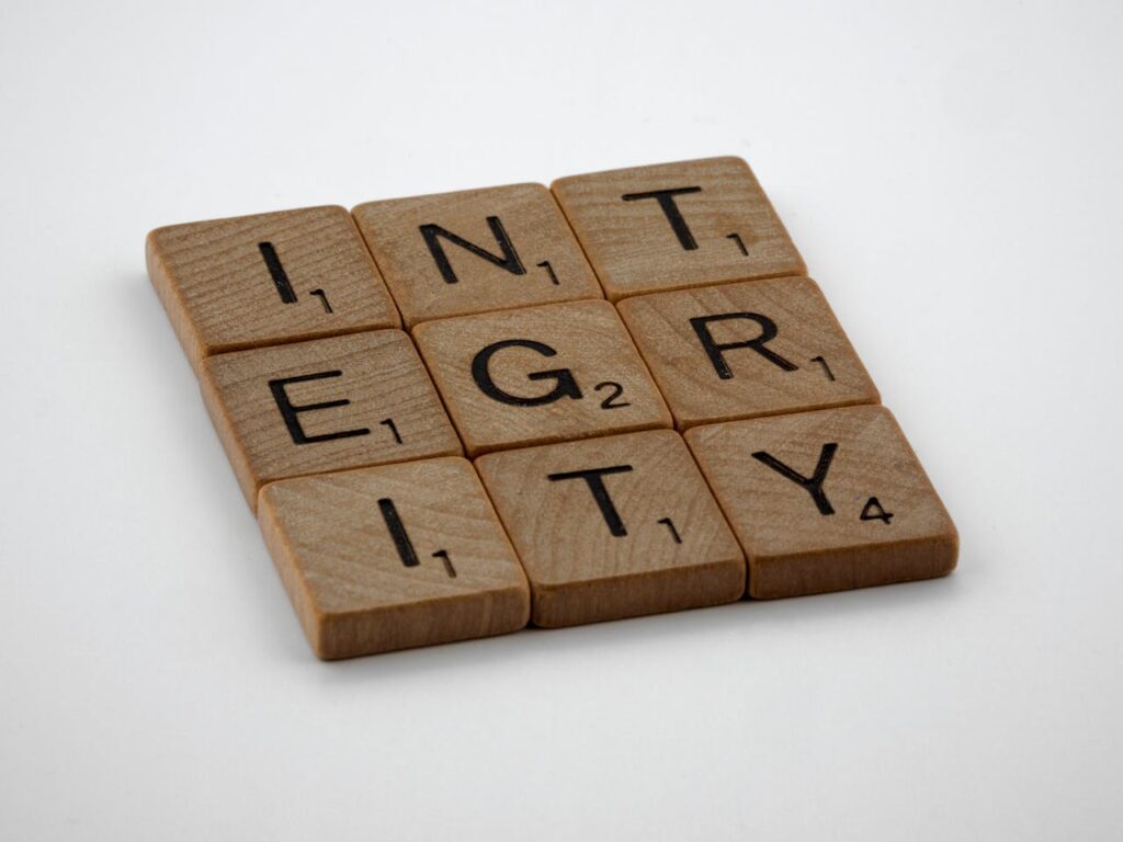 Wooden scrabble tiles spelling 'INTEGRITY' on a white background, emphasizing honesty and ethics.